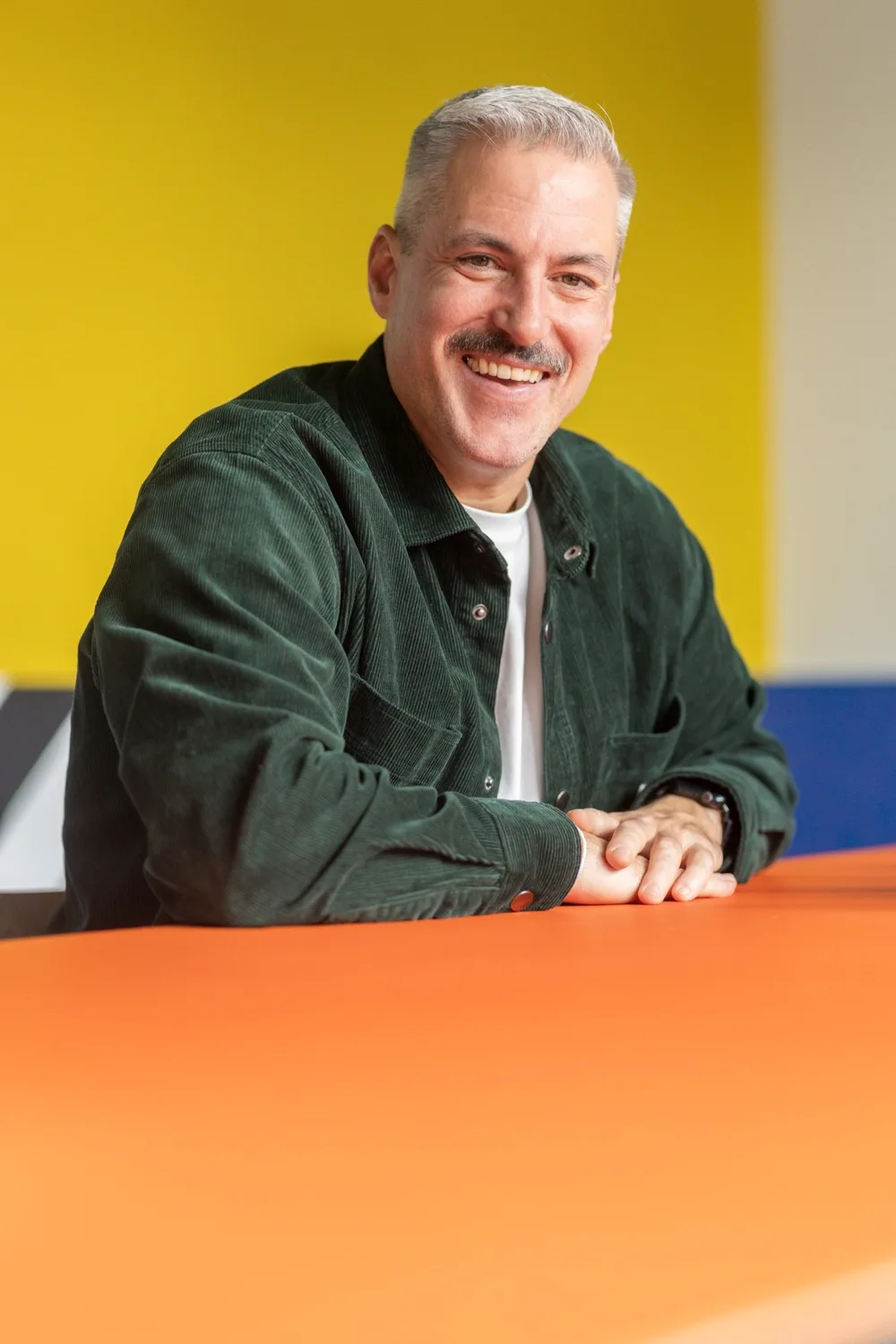 Marco Rühl, founder and managing director of la marchante GmbH, laughing at an orange table